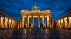 A symmetric low-angle shot of the Brandenburg Gate illuminated at twilight, deep blue sky, sharp arc